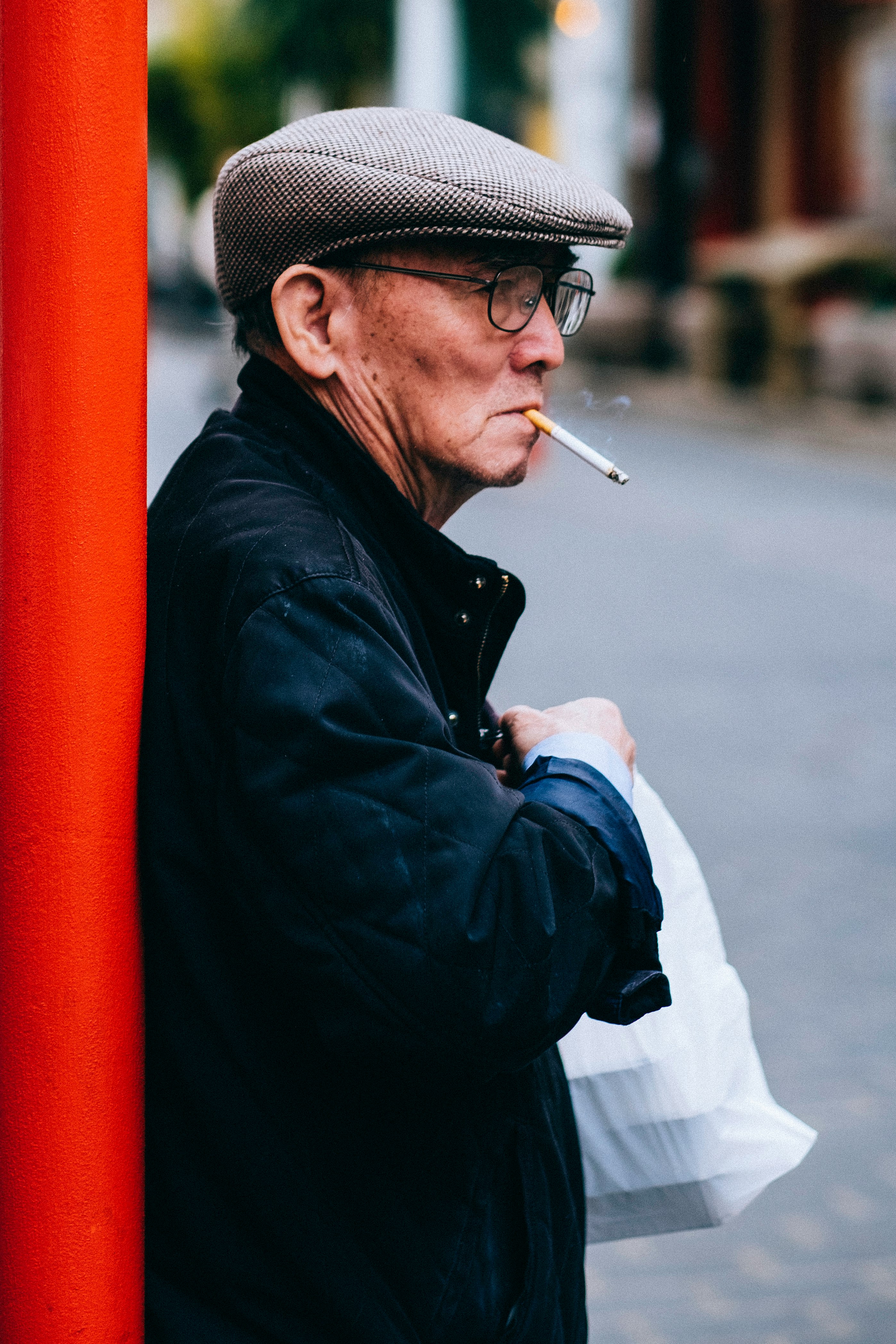 man standing beside post holding plastic bag